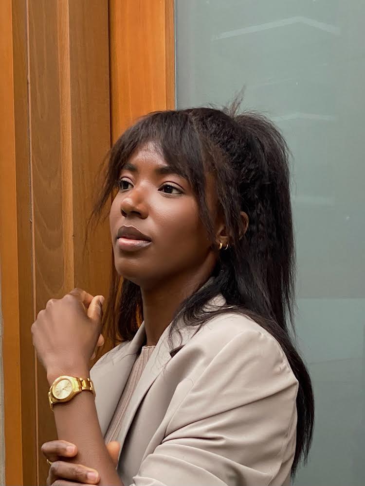 Woman wearing tan jacket and wearing a gold watch