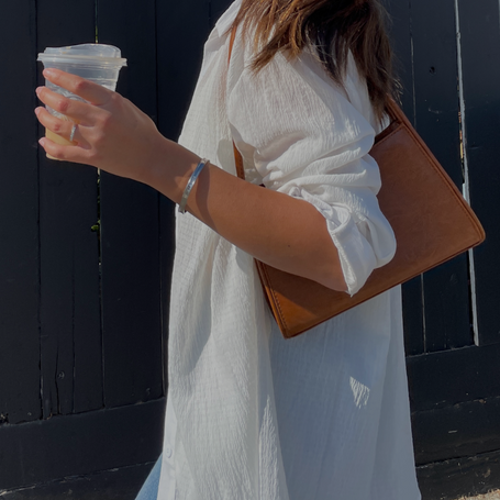 woman in a beige shirt, a brown bag and silver jewelry