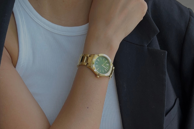 woman wearing a gold and green stainless steel watch 